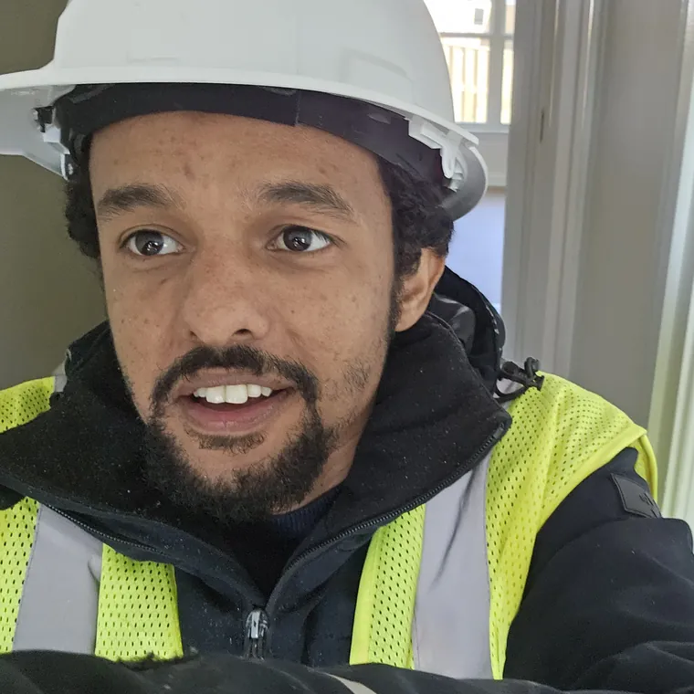 Memnon Solutions technician on site wearing a hard hat and high-visibility vest