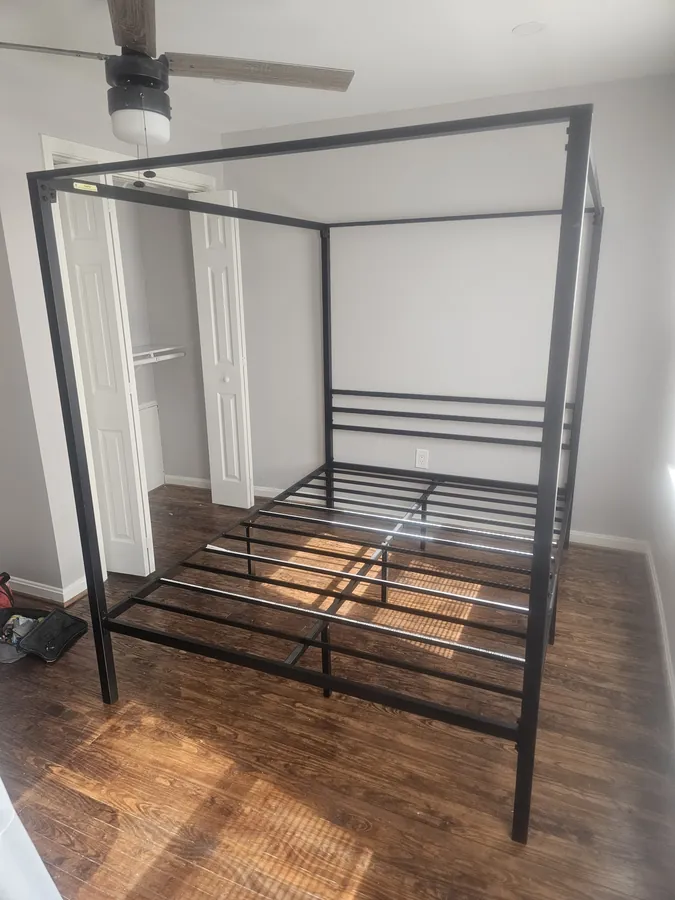 Four-poster canopy bed frame assembled in a bedroom