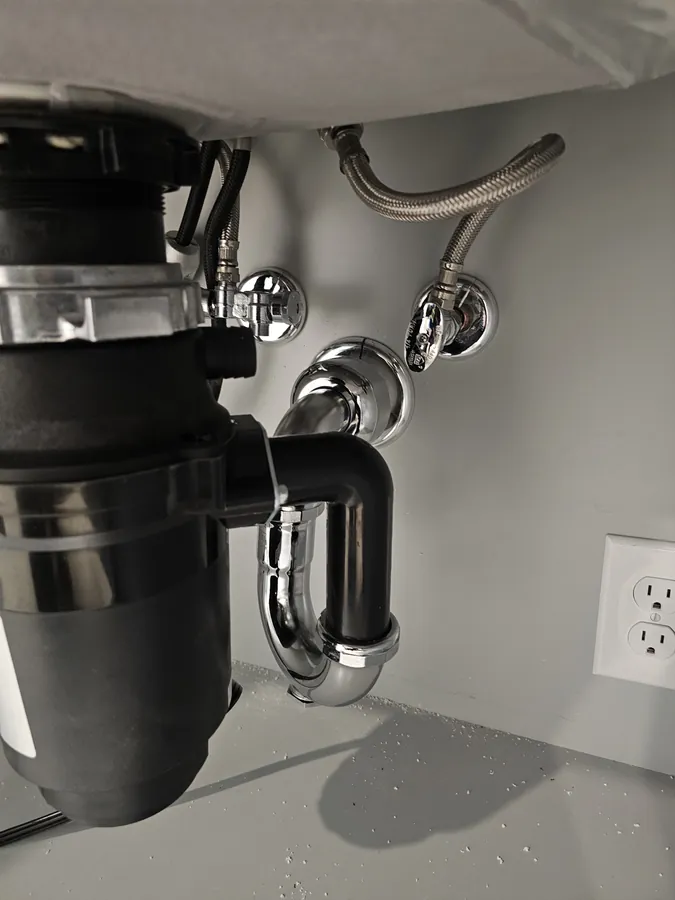 Garbage disposal unit fitted under a kitchen sink with new drain pipework