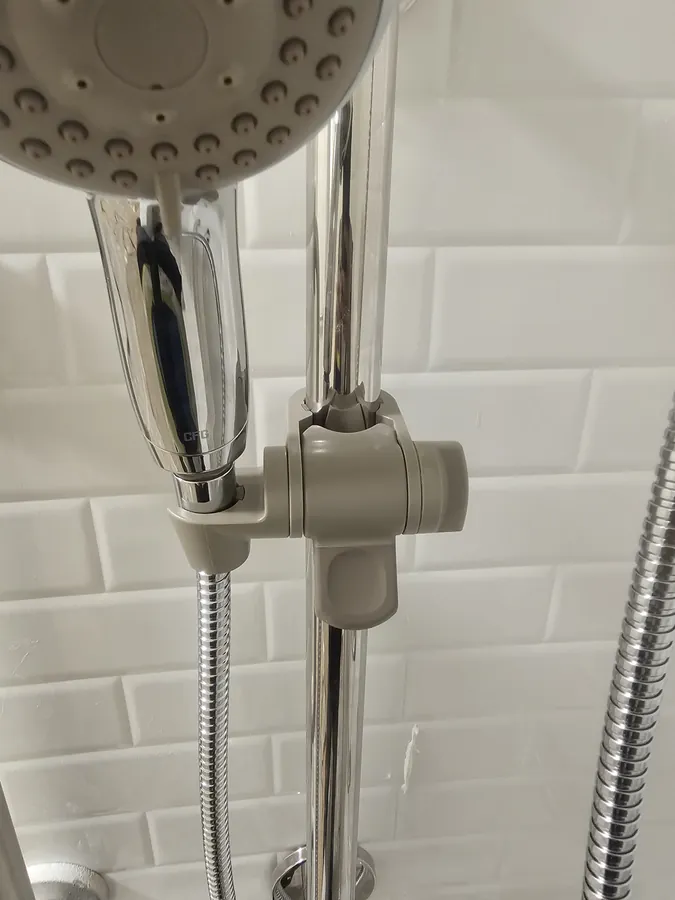 Hand shower on a slide bar fitted to a white tiled shower wall